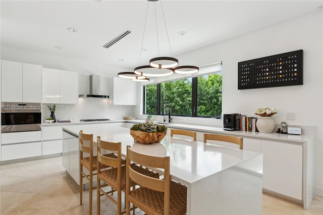 kitchen featuring pendant lighting, light countertops, white cabinetry, stainless steel oven, and a kitchen island