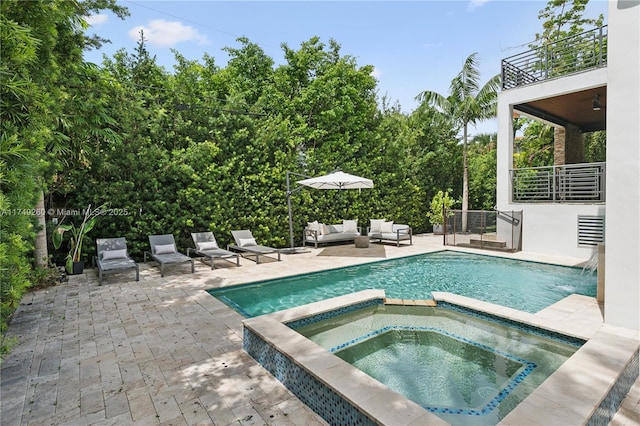 view of swimming pool featuring a pool with connected hot tub, outdoor lounge area, and a patio