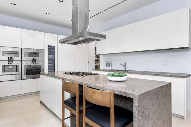 kitchen with a kitchen bar, island exhaust hood, white cabinets, and a center island