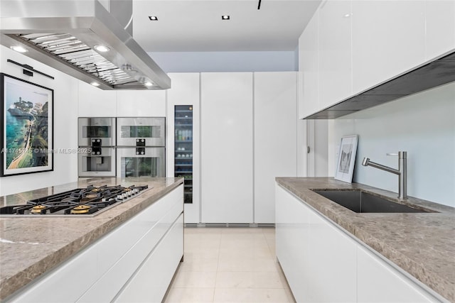 kitchen with island exhaust hood, a sink, white cabinets, and stainless steel gas stovetop