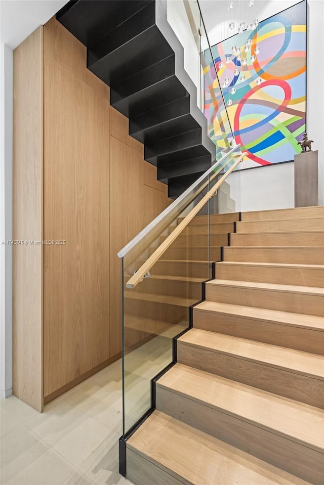 staircase with wood walls and tile patterned floors