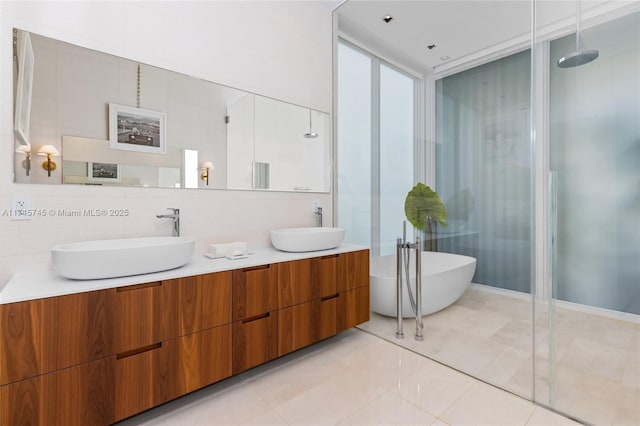 bathroom featuring a freestanding bath, double vanity, a sink, and tile patterned floors