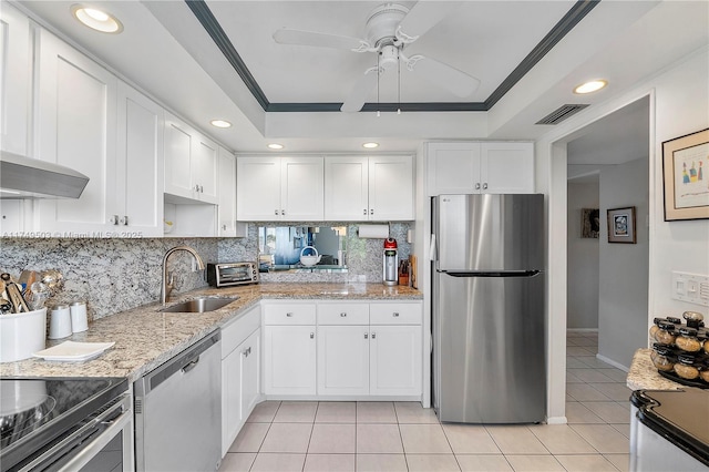 kitchen featuring a sink, appliances with stainless steel finishes, a raised ceiling, and white cabinets