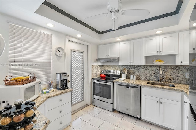 kitchen featuring white cabinets, a raised ceiling, appliances with stainless steel finishes, under cabinet range hood, and a sink