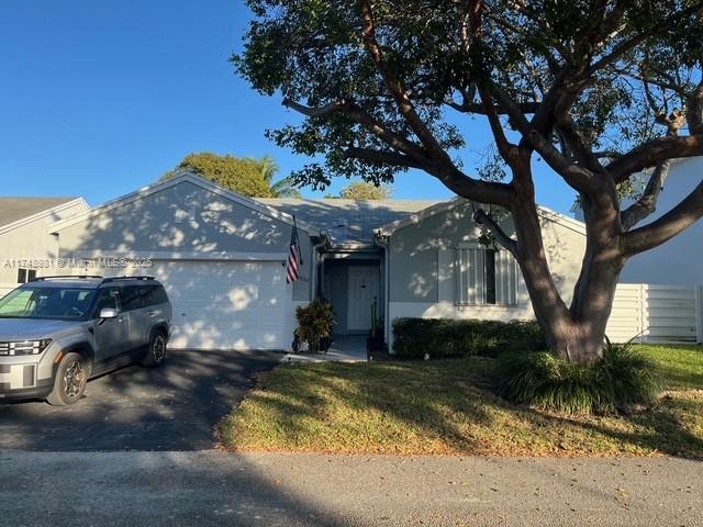 ranch-style home with a garage, driveway, and a front lawn