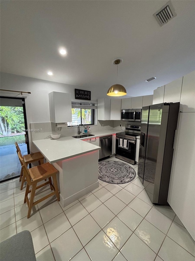 kitchen with visible vents, white cabinets, hanging light fixtures, stainless steel appliances, and light countertops