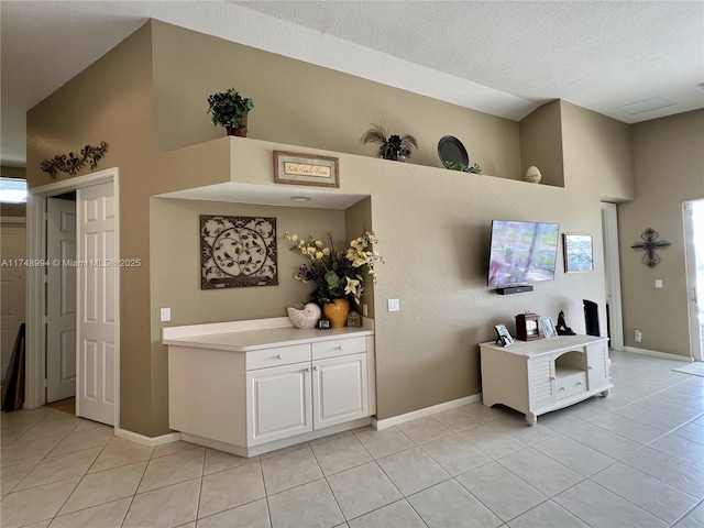 interior space featuring light tile patterned flooring, a textured ceiling, and baseboards