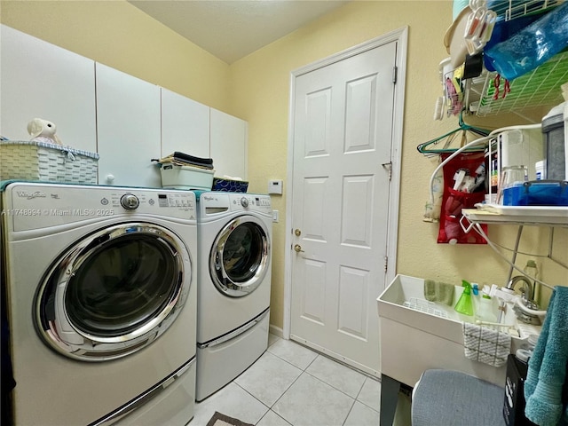 washroom with light tile patterned floors, washing machine and dryer, and cabinet space