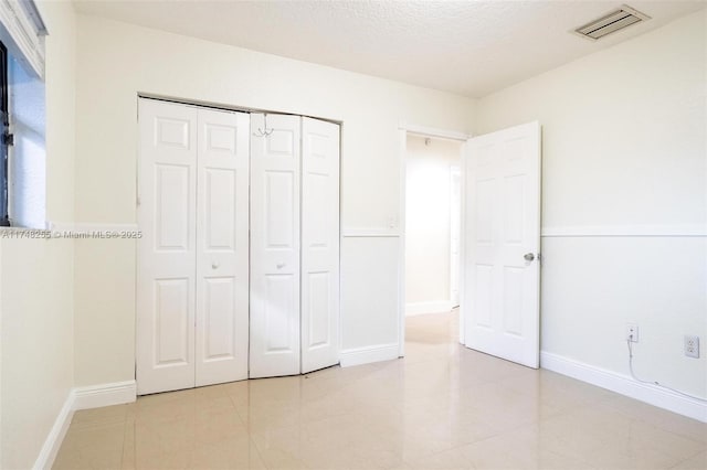 28451 SW 164th Ave, Homestead, FL 33033 - unfurnished bedroom with a closet, baseboards, a textured ceiling, and light tile patterned floors