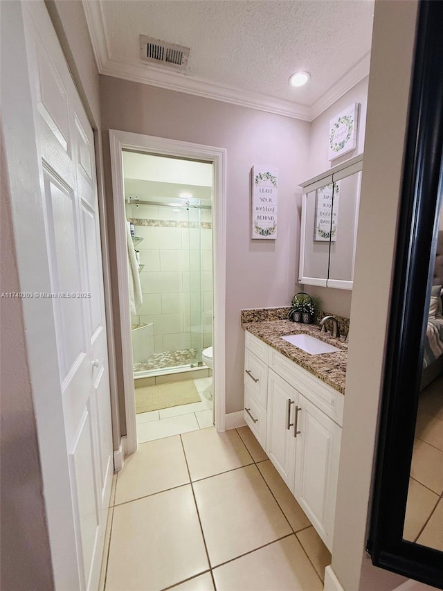 bathroom featuring visible vents, toilet, vanity, a textured ceiling, and crown molding