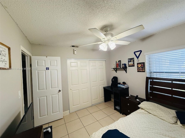 bedroom featuring light tile patterned floors, visible vents, a ceiling fan, a textured ceiling, and a closet