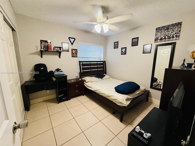 bedroom with light tile patterned floors, ceiling fan, a textured ceiling, baseboards, and a closet