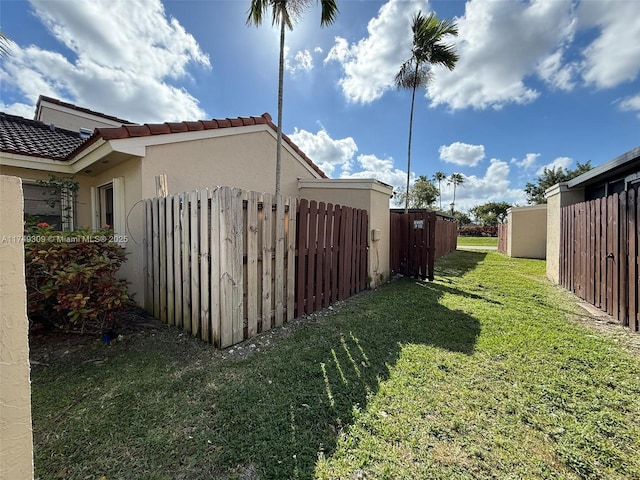 view of home's exterior with stucco siding, a tiled roof, fence, and a yard