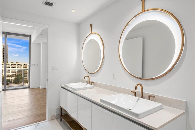 full bathroom with double vanity, a sink, visible vents, and baseboards