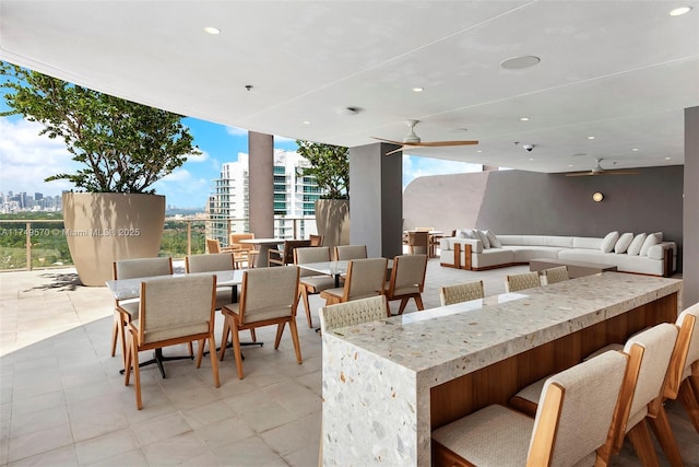 view of patio / terrace with a city view, ceiling fan, an outdoor living space, and an outdoor bar