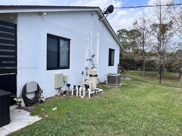 view of property exterior featuring central AC, fence, a lawn, and stucco siding