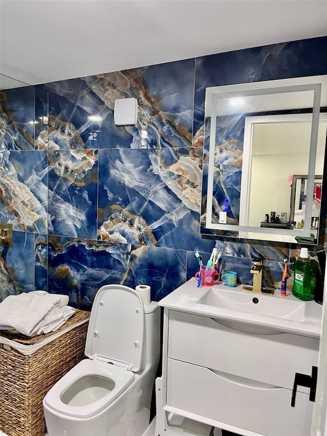 bathroom with toilet, tile walls, and vanity