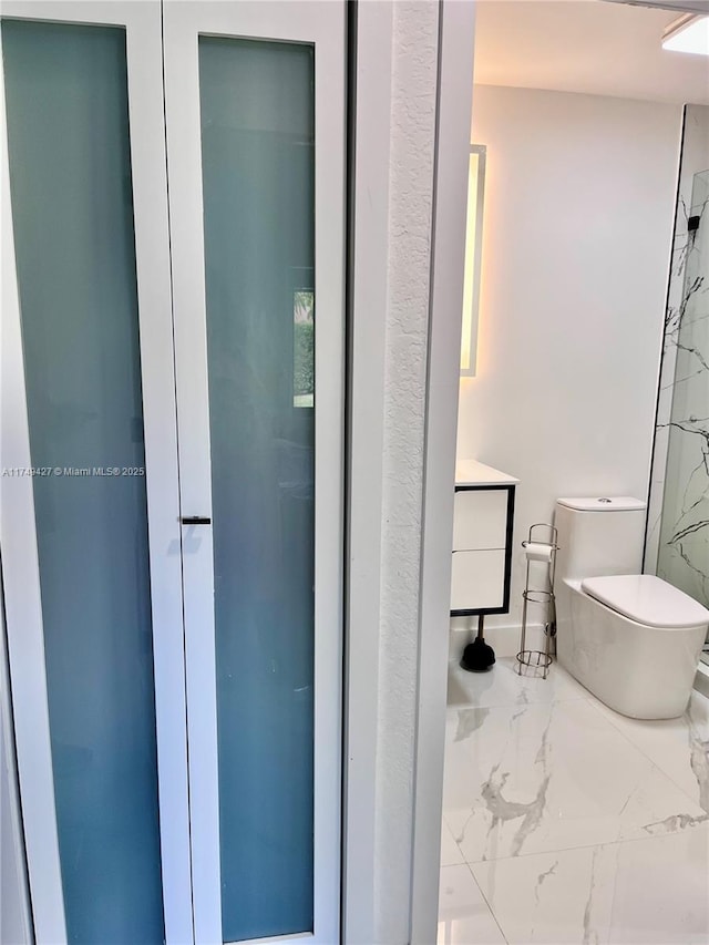 bathroom with marble finish floor and toilet