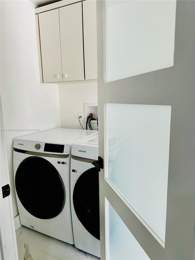 washroom with marble finish floor, washing machine and dryer, and cabinet space