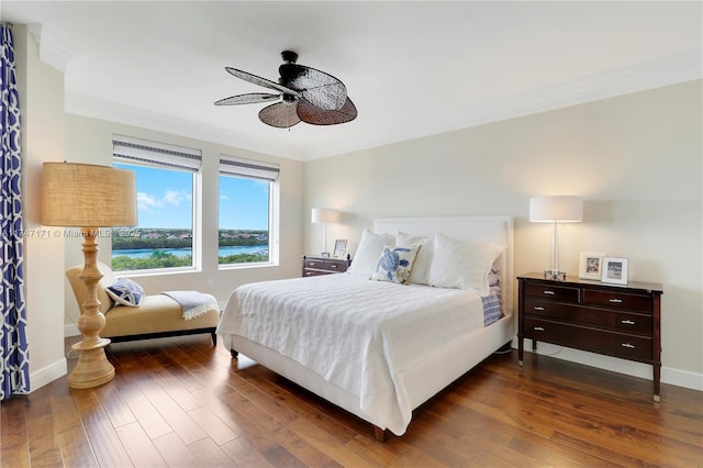 bedroom featuring ornamental molding, dark wood-style flooring, a water view, and baseboards