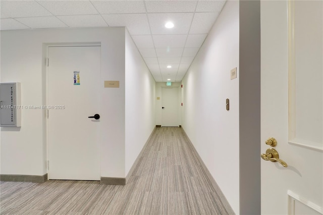 hall featuring a paneled ceiling, baseboards, and recessed lighting