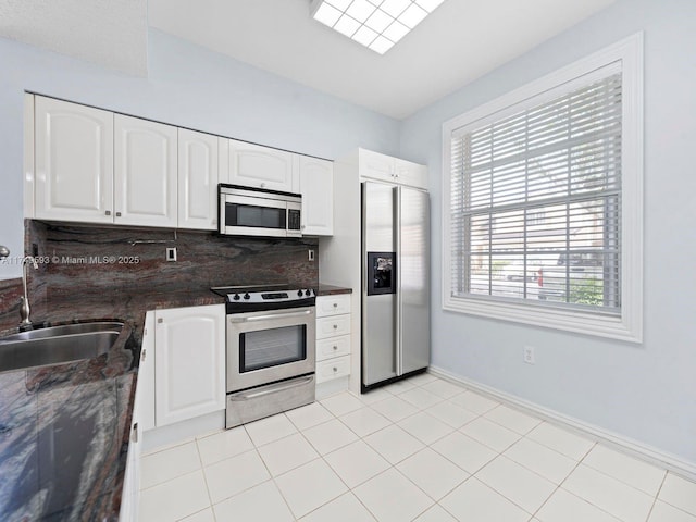 kitchen featuring stainless steel appliances, white cabinetry, a sink, and backsplash