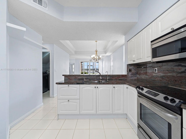 kitchen with visible vents, white cabinets, appliances with stainless steel finishes, decorative backsplash, and a tray ceiling