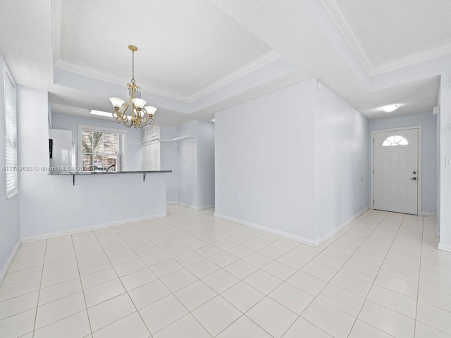 foyer entrance featuring baseboards, a raised ceiling, ornamental molding, a textured ceiling, and a notable chandelier