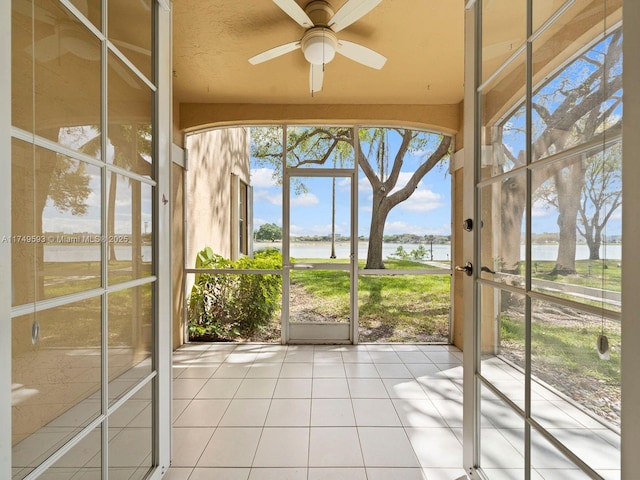 unfurnished sunroom featuring ceiling fan and a water view