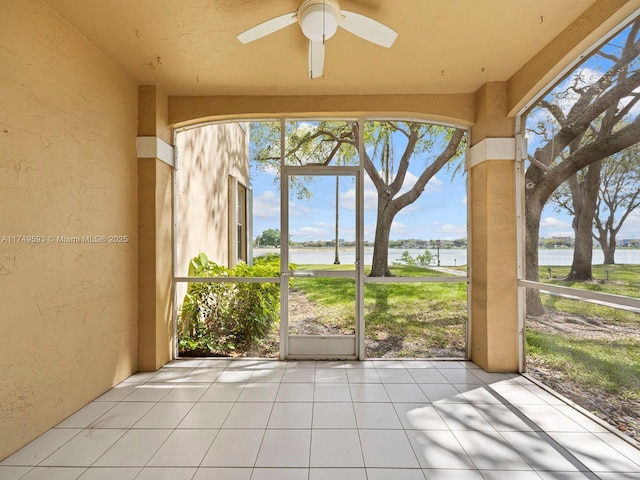 unfurnished sunroom with a water view and a ceiling fan