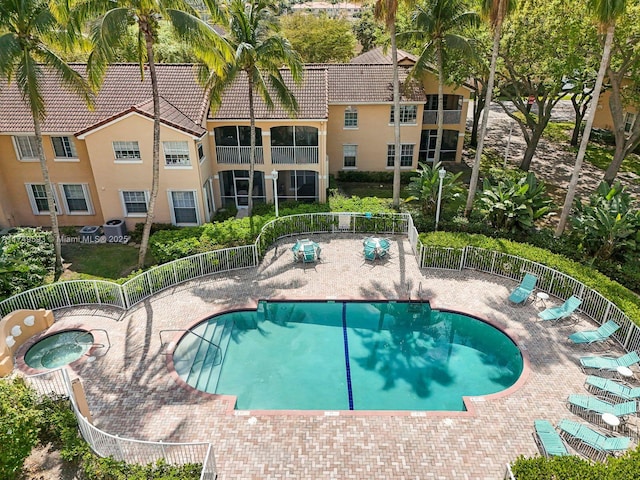 community pool featuring a community hot tub and fence