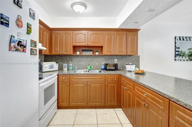 kitchen with white appliances, under cabinet range hood, decorative backsplash, and a sink