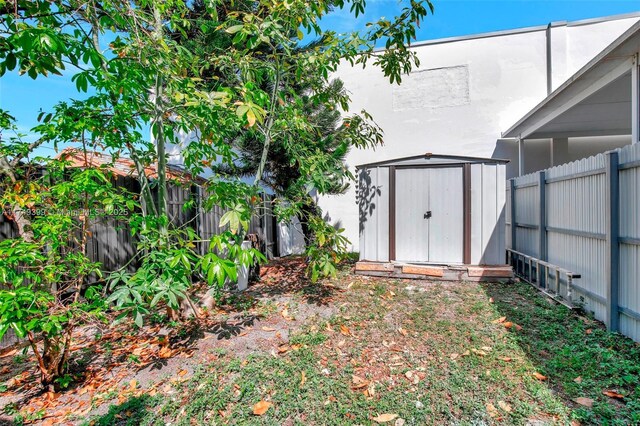 view of yard with a fenced backyard, an outdoor structure, and a storage unit