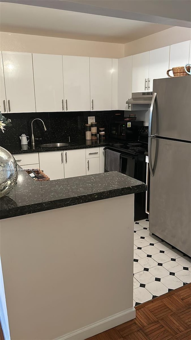 kitchen with black electric range, freestanding refrigerator, white cabinetry, dark stone countertops, and under cabinet range hood