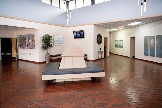 interior space with brick floor, a towering ceiling, and baseboards