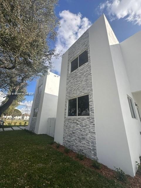 view of side of home with a lawn and stucco siding