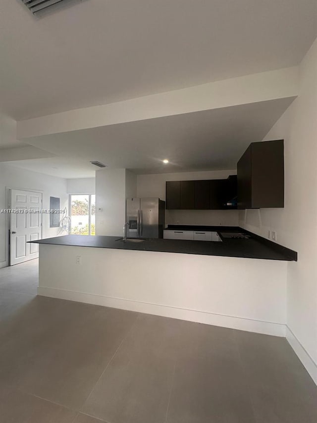 kitchen with dark countertops, visible vents, baseboards, stainless steel refrigerator with ice dispenser, and a sink