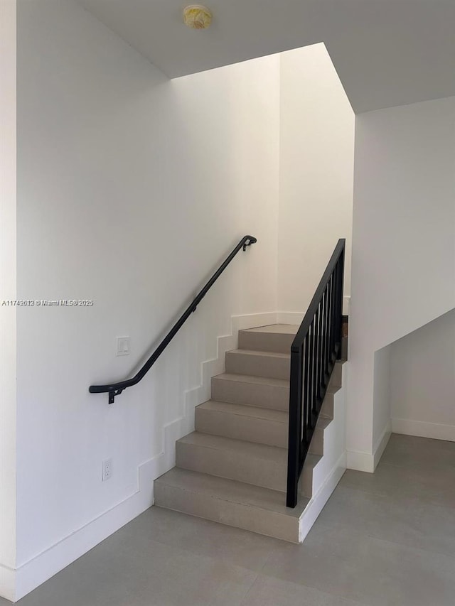 stairway featuring concrete floors and baseboards