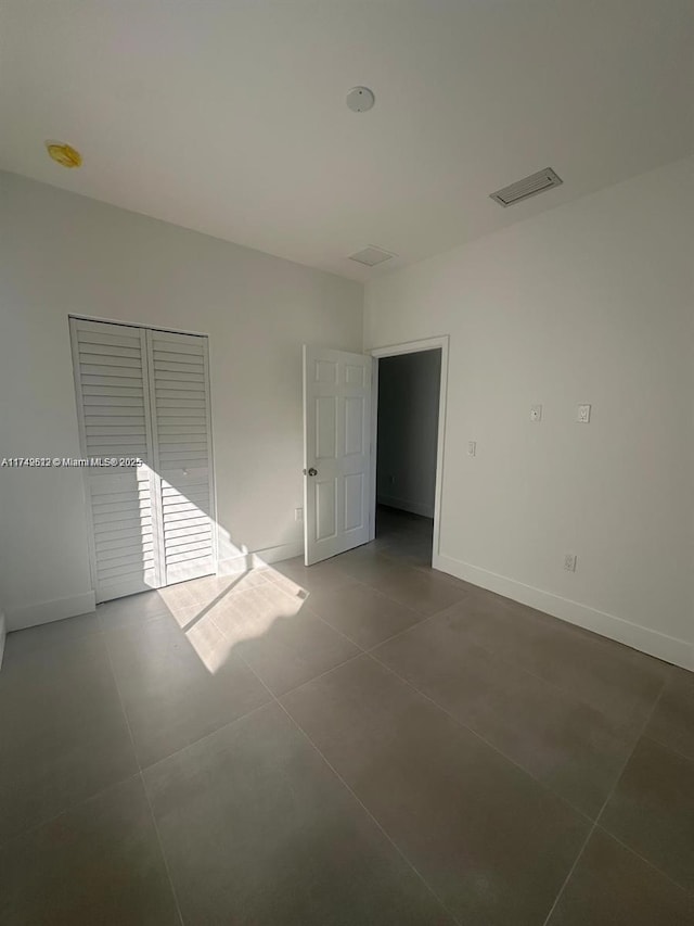 unfurnished room with tile patterned flooring, visible vents, and baseboards