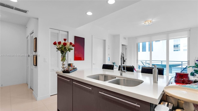 kitchen with visible vents, modern cabinets, light countertops, dark brown cabinets, and a sink