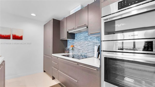 7875 NW 107th Ave Unit 511, Doral, FL 33178 - kitchen with decorative backsplash, black electric cooktop, light countertops, stainless steel double oven, and under cabinet range hood