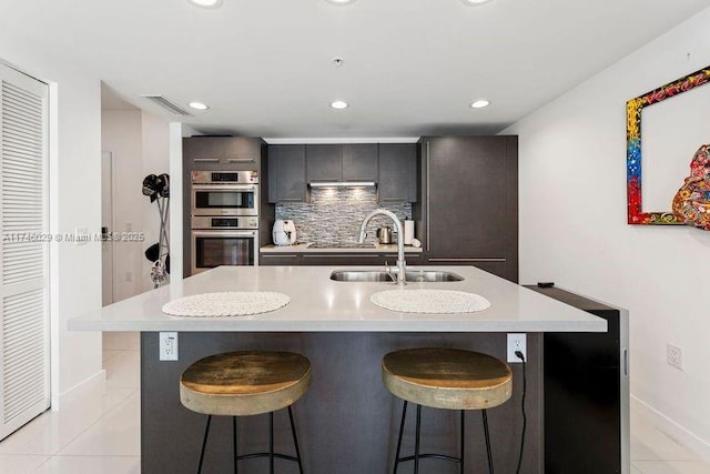 7875 NW 107th Unit 705, Doral, FL 33178 - kitchen featuring a breakfast bar, a kitchen island with sink, light countertops, and a sink