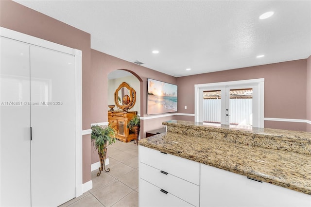 kitchen featuring light tile patterned floors, light stone counters, french doors, white cabinetry, and recessed lighting