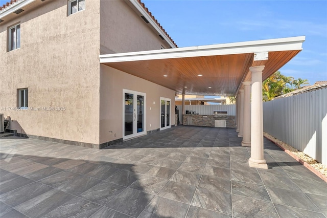 view of patio featuring central air condition unit, fence, exterior kitchen, and french doors