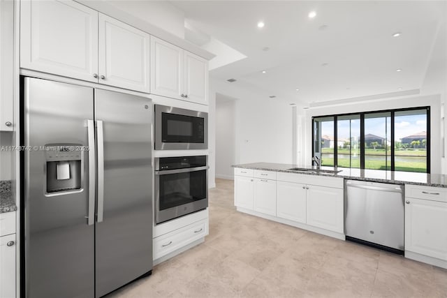 kitchen featuring a sink, stone counters, appliances with stainless steel finishes, and white cabinets