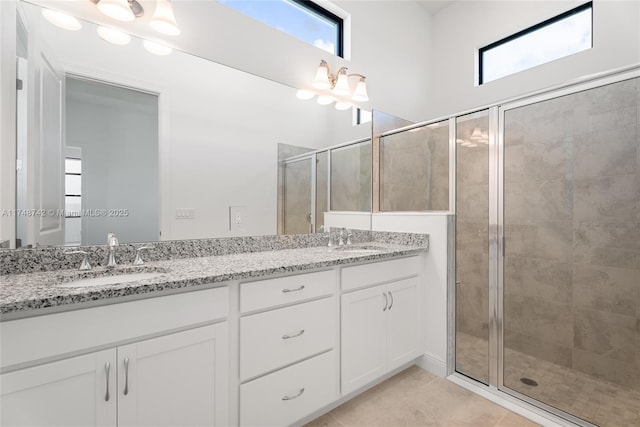 bathroom with a shower stall, double vanity, tile patterned floors, and a sink