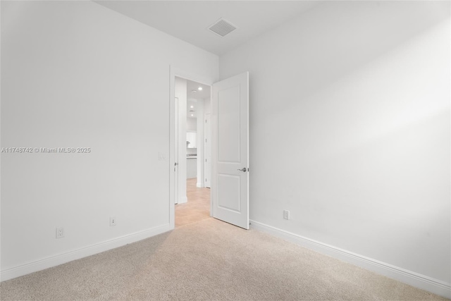 unfurnished room featuring light colored carpet, visible vents, and baseboards