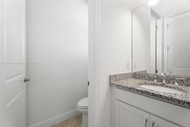 bathroom with toilet, vanity, and baseboards