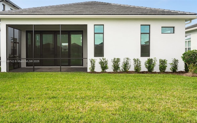 rear view of property featuring stucco siding, a tile roof, a yard, and a sunroom