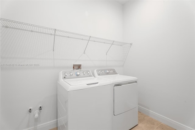 clothes washing area with laundry area, baseboards, and washing machine and clothes dryer